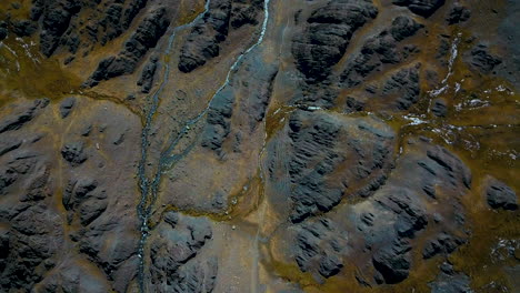 vista aérea de arriba hacia abajo de un río que corre sobre un paisaje escarpado y estéril