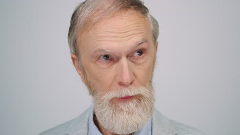 serious man posing to camera in studio. aged gentleman feeling confused indoors.