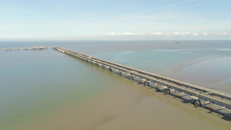 Drone-Aerial-View-of-Concrete-Oil-Pier-Construction-Above-Shallow-Water-of-North-Sea