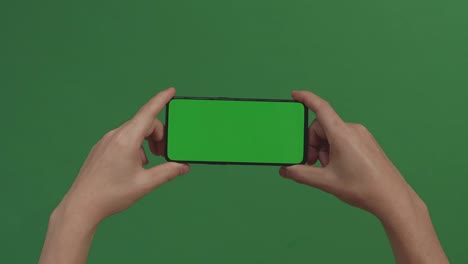hands holding cell phone with green screen in green background