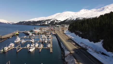 drone montant sur une marina à whittier alaska pins et montagnes enneigées en arrière-plan