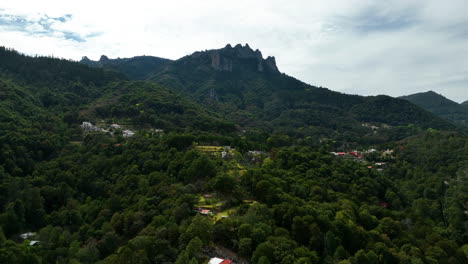 Disparo-De-Un-Dron-Sobre-Casas,-Hacia-Los-Picos-De-Rocas-De-La-Bruja-Del-Parque-Nacional-El-Chico,-México