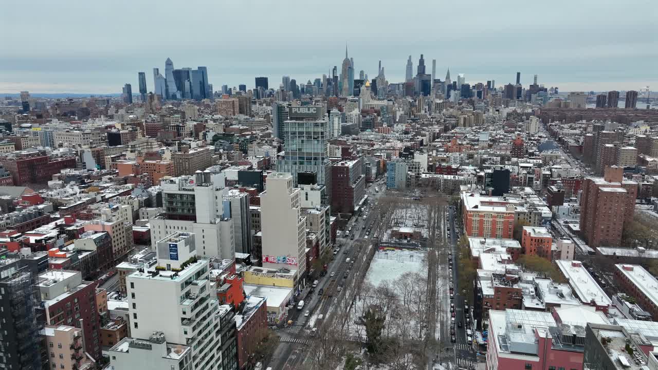 Luftfoto af hovedgaden i en amerikansk forstad med lejlighedskomplekser og Manhattans skyline i det fjerne. Bredt billede. Sneklædt vinterdag i Amerika