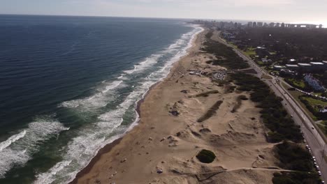 Sobrevuelo-Aéreo-Playa-De-Arena-Con-Dunas-Y-Hermoso-Océano-Durante-La-Puesta-De-Sol---Playa-Brava,-Punta-Del-Este