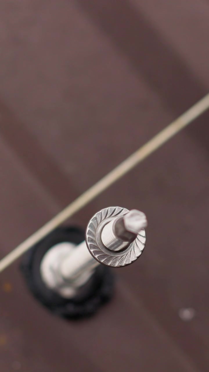 Close-up de um detalhe de parafuso e corda com uma chave inglesa em uma superfície marrom, vídeo vertical
