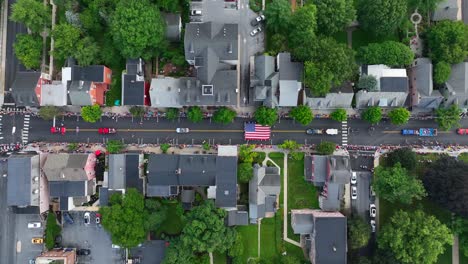 Ein-Riesiges,-Mit-Sternen-übersätes-Banner-Wird-Die-Hauptstraße-Einer-Kleinen-Amerikanischen-Stadt-Hinaufgetragen