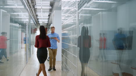 business man looking tablet in hallway. people going on modern office interior.