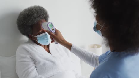 doctora afroamericana y paciente mayor con máscaras faciales