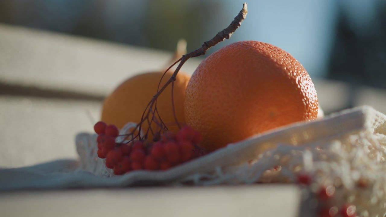 Friske appelsiner og røde bær i en netpose.
