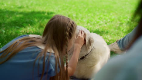 niña linda abrazando a un labrador en un picnic en el parque. niño alegre acurrucando al perro al aire libre