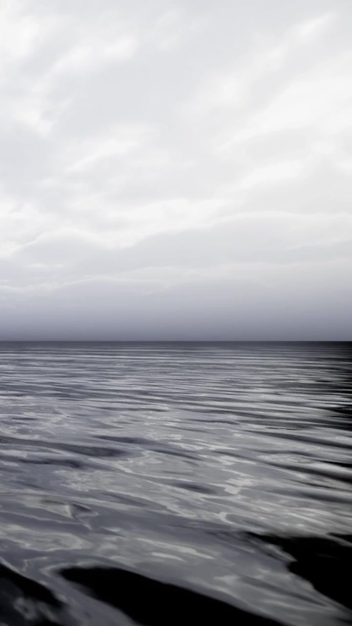 Calm water reflects gray skies over a distant coastline near the ocean