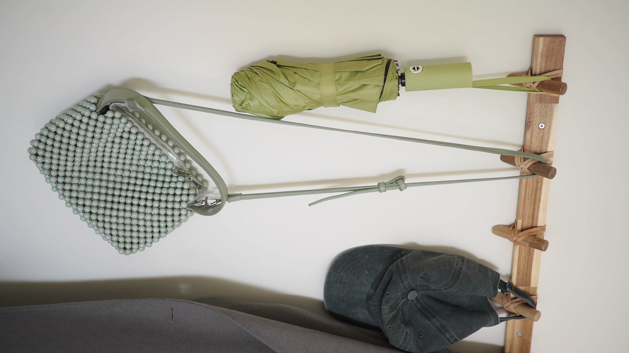 Hand Removes Green Knitted Bag from Wooden Wall Hook