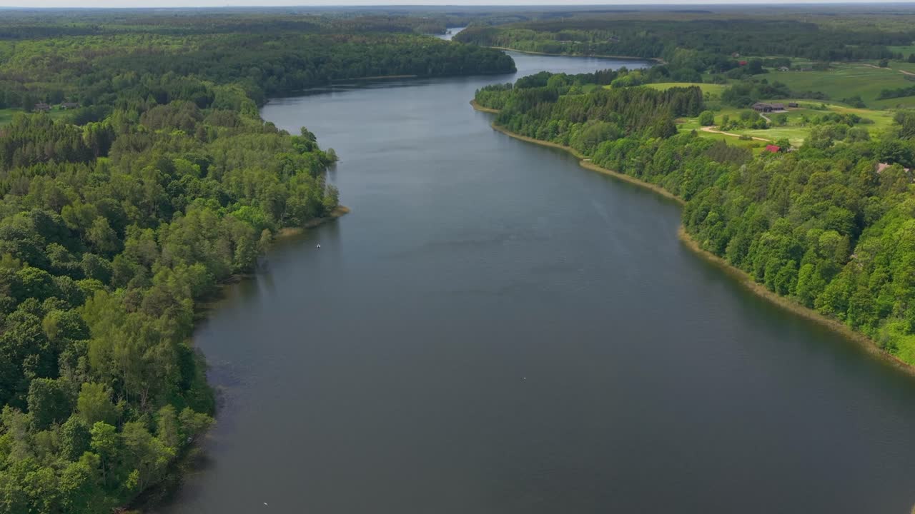 Aerial view of a wide calm river winding through lush green forests and countryside, captured on a sunny summer day