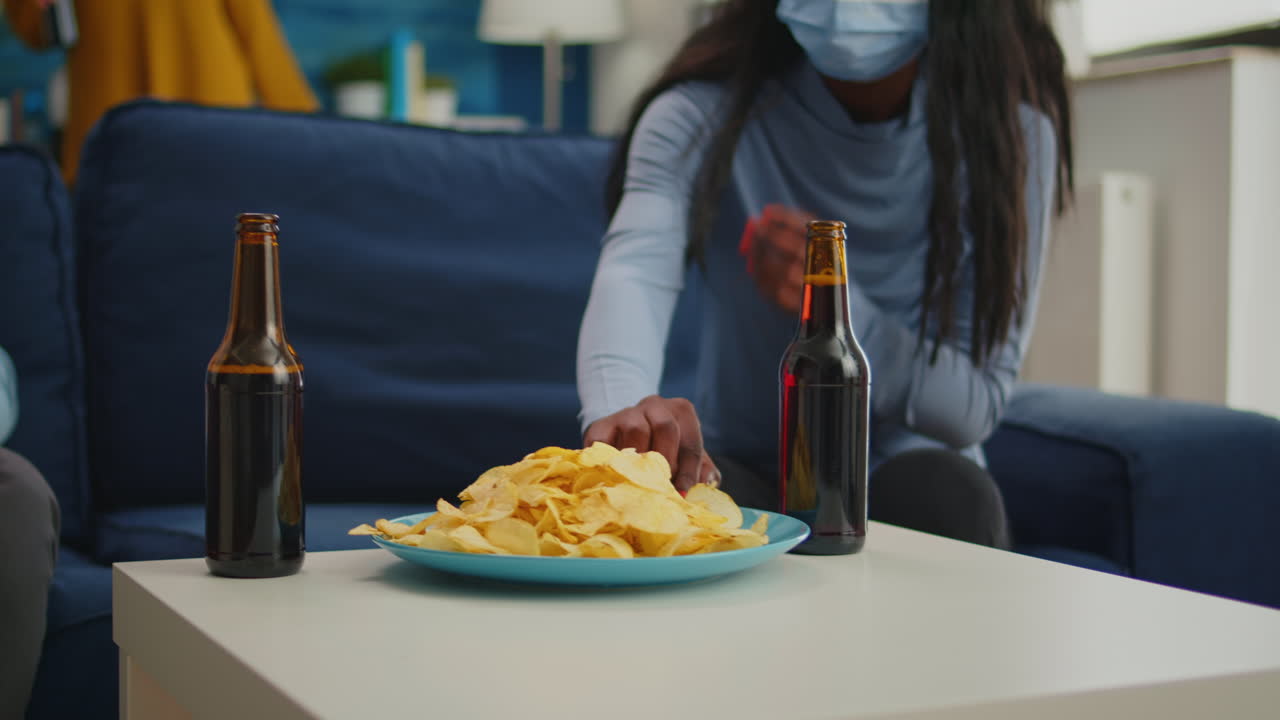 Close up of multiracial friends taking off protection mask and eating