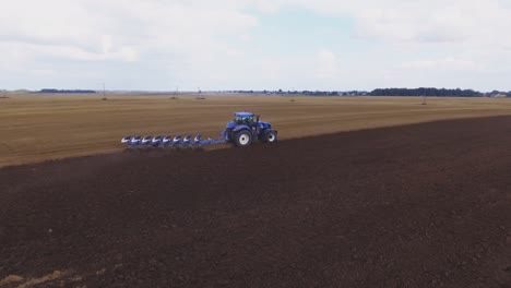 blue modern plowing tractor working in the field-4