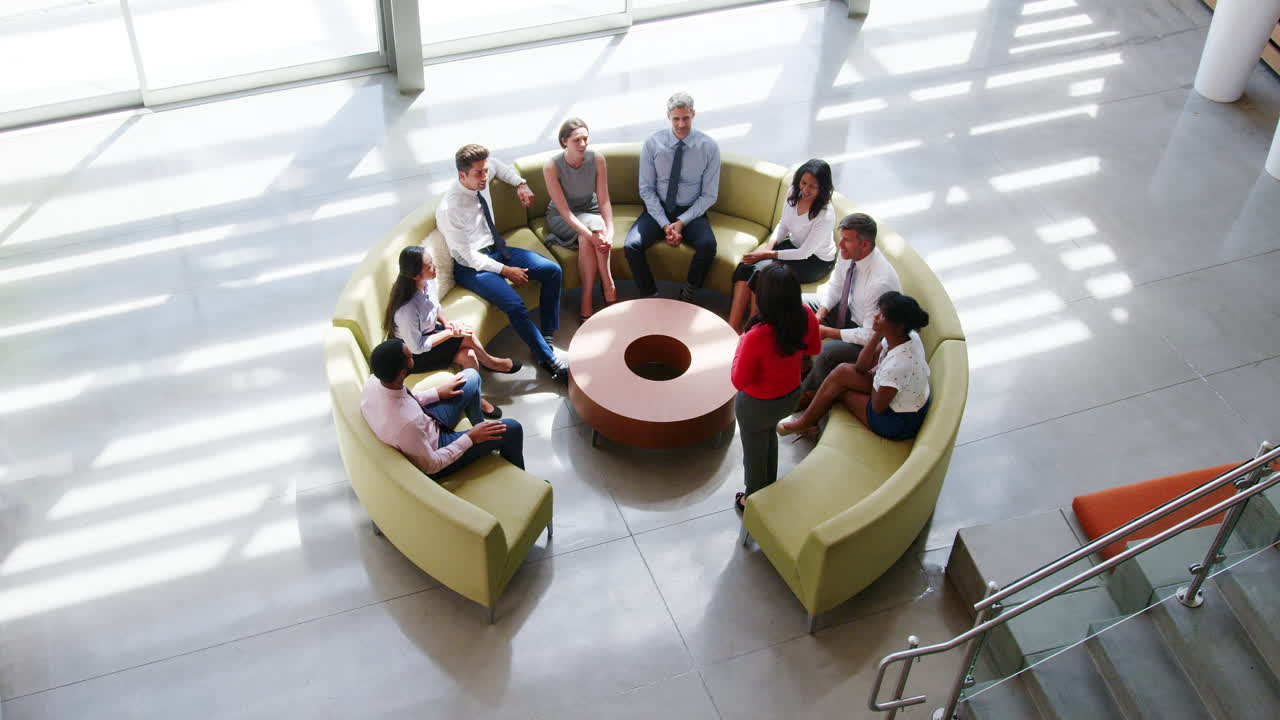 Businesswoman stands presenting at a meeting, elevated view