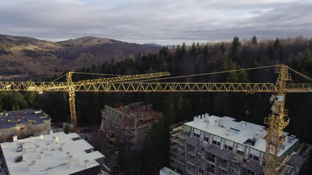 vista aérea de grúas en un sitio de construcción en una montaña cubierta de bosque