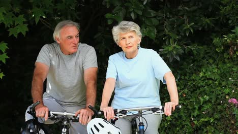 elderly couple walking with their bikes