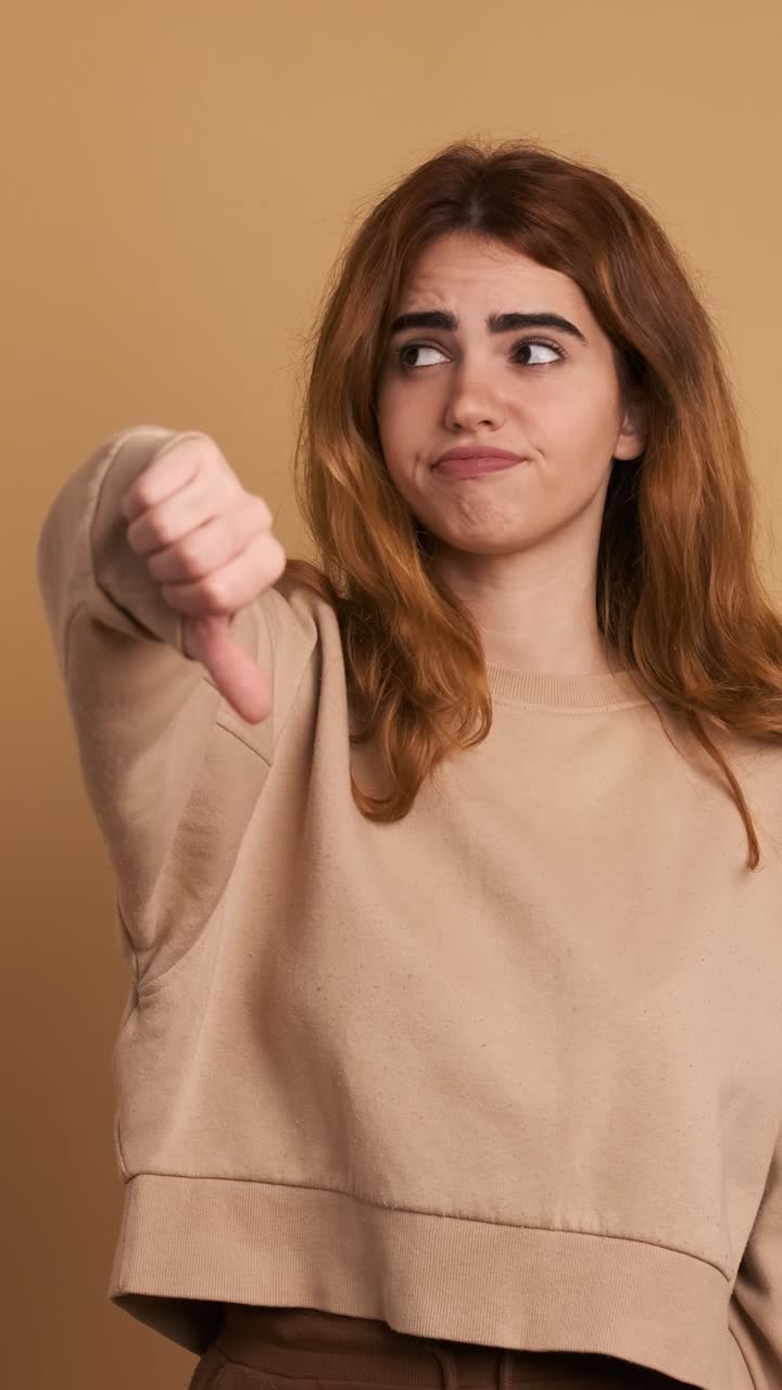 Young woman gesturing disagreement with thumb down. Vertical Footage