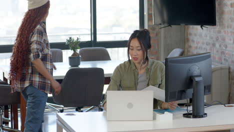 diverse female team collaborating in modern office, using laptop and discussing project ideas
