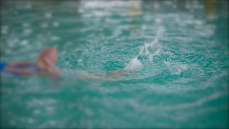 young girl is practicing how to swim on a board inside indoor swimming hall