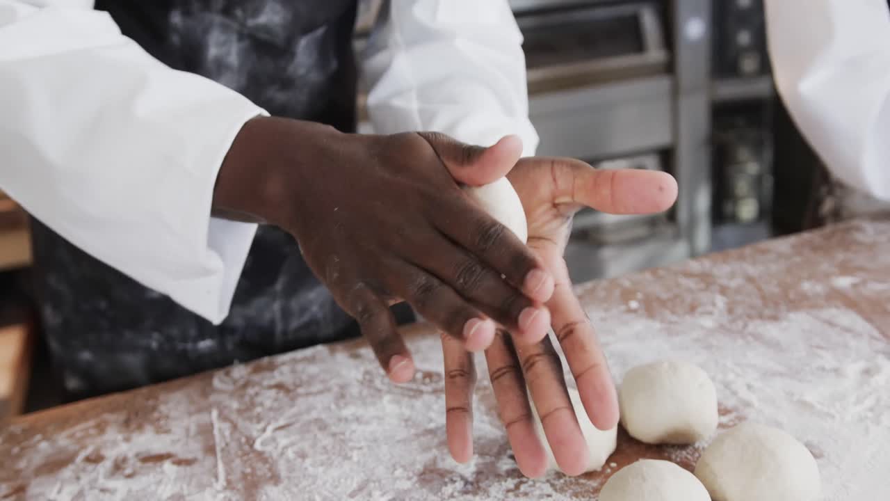 Diverse bakers working in bakery kitchen, making rolls from dough in slow motion