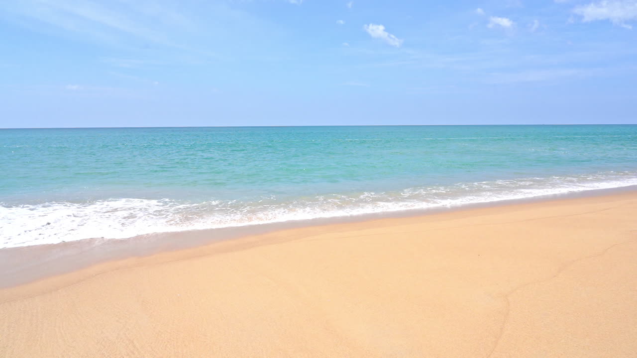 거품이 많은 작은 바다 파도가 부드러운 노란 모래사장, 자연 배경 위에 부서지고 튀고 있습니다.