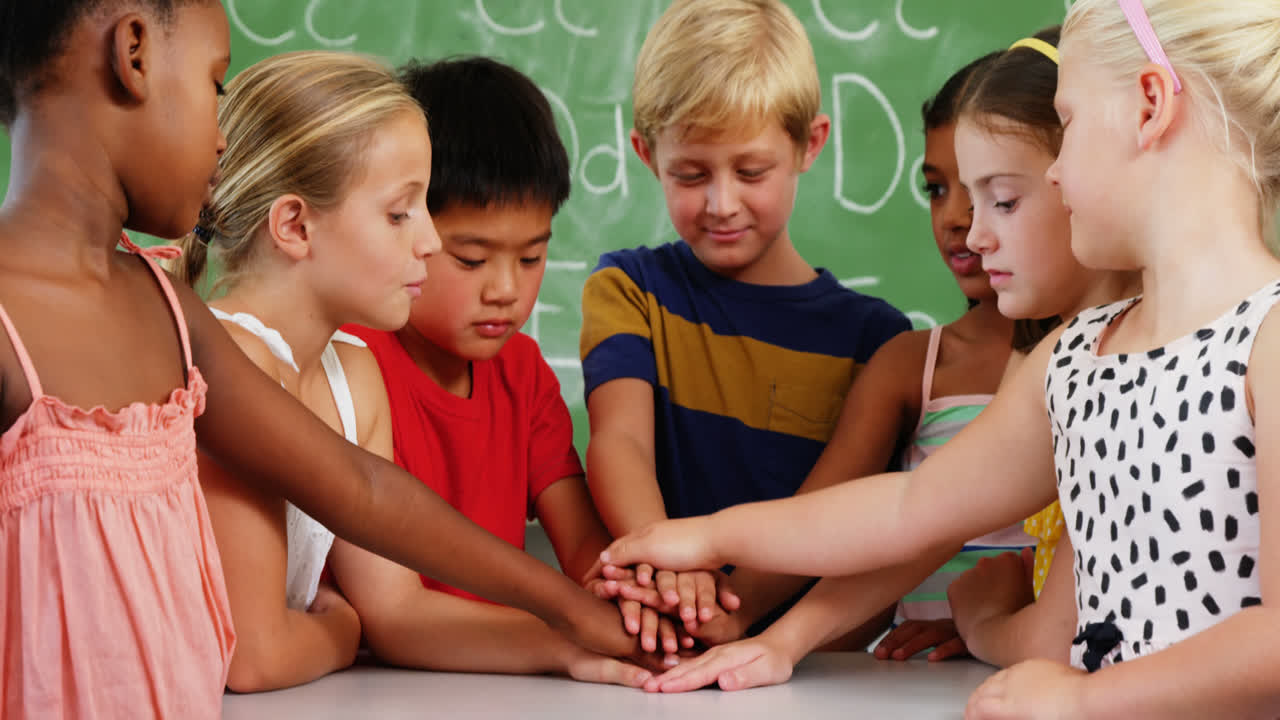 niños de la escuela apilando las manos en el aula