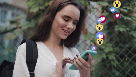 young woman interacting with social media on her smartphone with floating reaction emojis