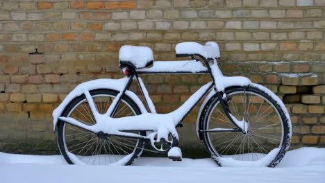 bicycle covered in snow against a brick wall