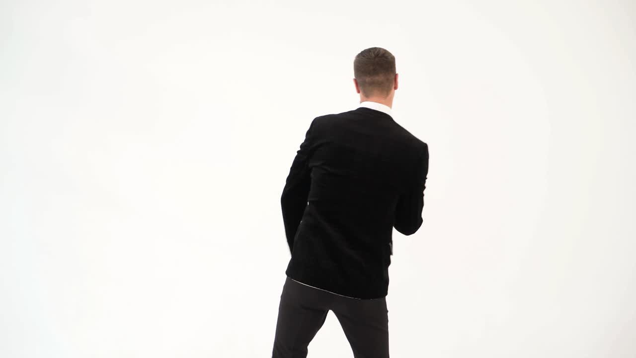 fun man in a black suit with a bow tie is showing dance of dancer on the white background