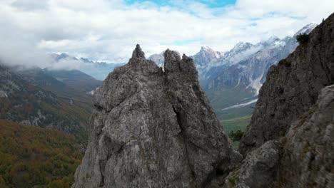 High-rocky-peak-of-a-mountain-in-the-Alps-with-an-amazing-background-of-valley,-forestry,-and-clouds