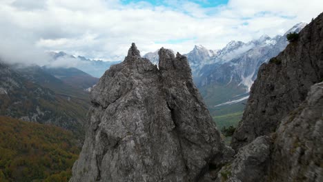 alto pico rocoso de una montaña en los alpes con un increíble fondo de valle, silvicultura y nubes