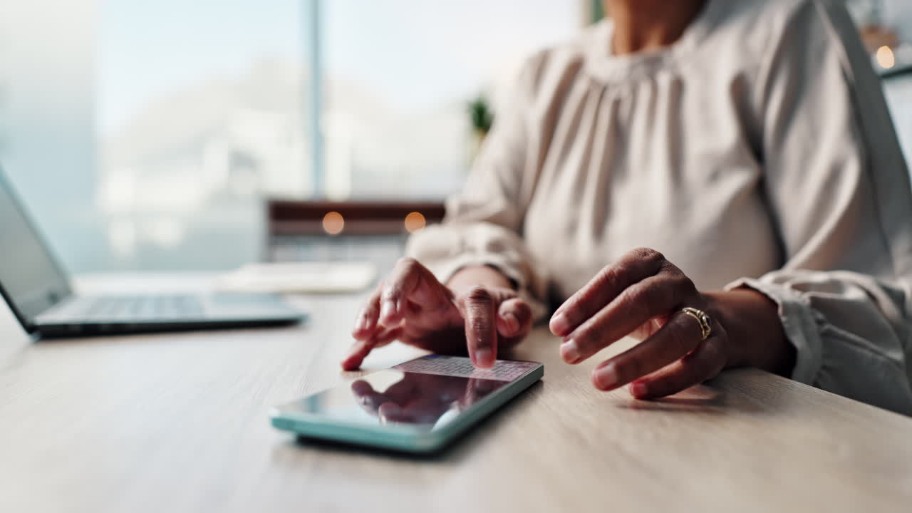 Woman using a mobile phone with a laptop on the desk
