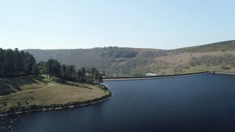 aerial shot over kinder reservoir water showing the dam wall and the hills on the far side