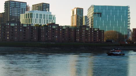 a boat floating in the river thames, london with a city building in background.