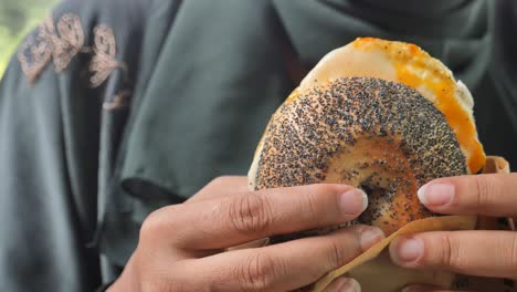 woman eating a poppy seed bagel with egg and cheese