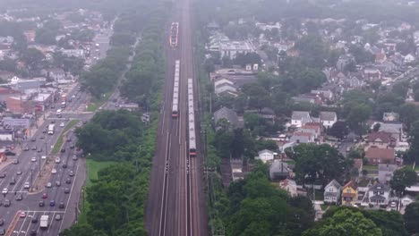 an aerial view of two long island rail road trains traveling on a cloudy day. the drone camera tilted downward, dolly in following the trains moving towards new york city together.