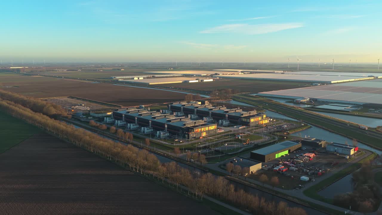 Flyfoto av datasenterkampus ved soloppgang med vindturbiner i bakgrunnen