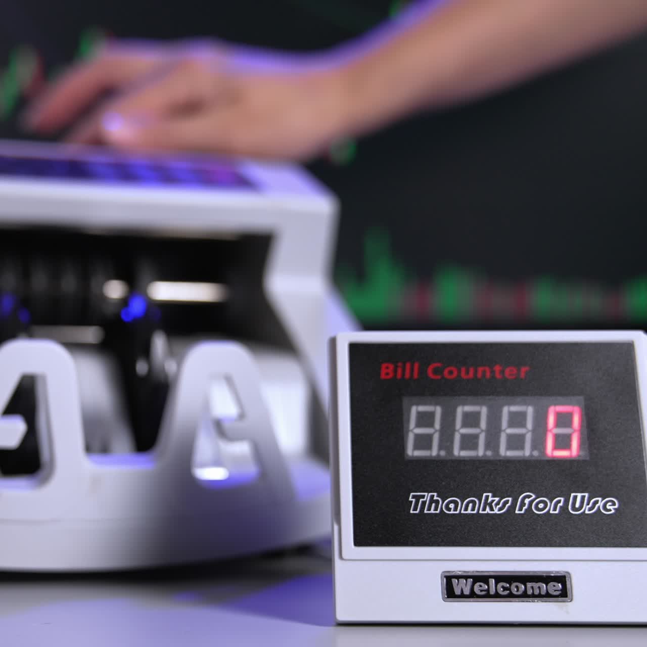 Modern cash counter machine on the table. Hand is putting a large amount of paper money into electronic machine for counting operation