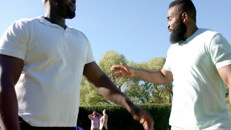 two diverse friends greeting each other with handshake outdoors, enjoying sunny day