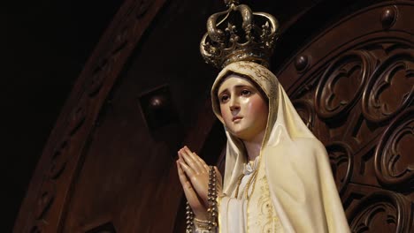 elegant statue of virgin mary in prayer with a golden crown and rosary
