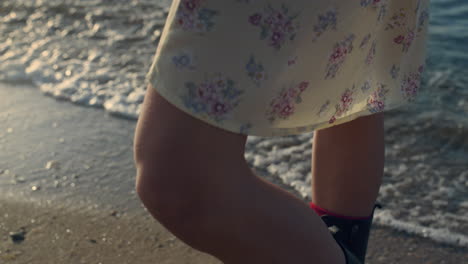 piernas de mujer casual de pie en una playa de arena. niña disfrutando de su tiempo de ocio en el mar