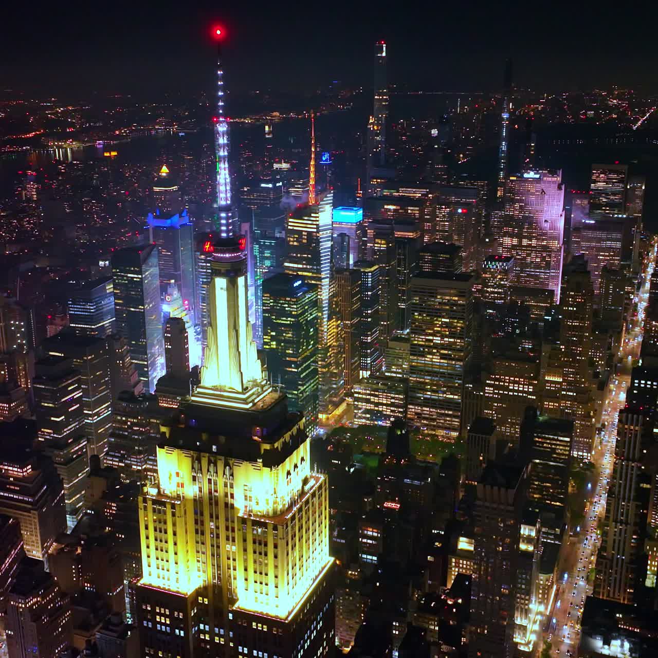The Empire State Building roof highlighted by bright yellow light at night. Outstanding skyscraper at the backdrop of New York panorama