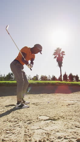 video vertical de un jugador de golf afroamericano jugando en un campo de golf en un día soleado