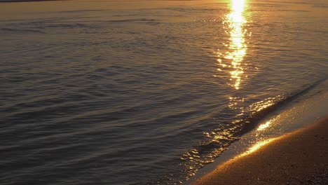 Tranquilas-Olas-Poco-Profundas-En-La-Orilla-Arenosa-Que-Reflejan-El-Amanecer,-El-Paisaje-Costero-Mediterráneo