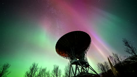 northern lights in sky with stars above parabolic research antenna, time lapse