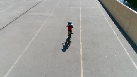 boy in helmet riding bicycle on asphalt road, aerial view