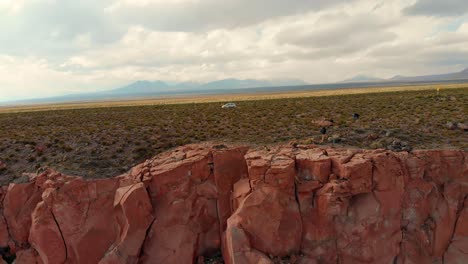 aerial cinematic view distancing of a lonely car on a road near a canyon in atacama desert at sunset