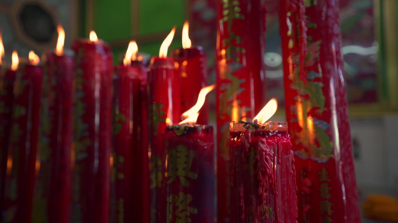 Candele accese in un tempio buddista cinese, che creano un bagliore caldo in un ambiente spirituale sacro, primo piano dettagliato.